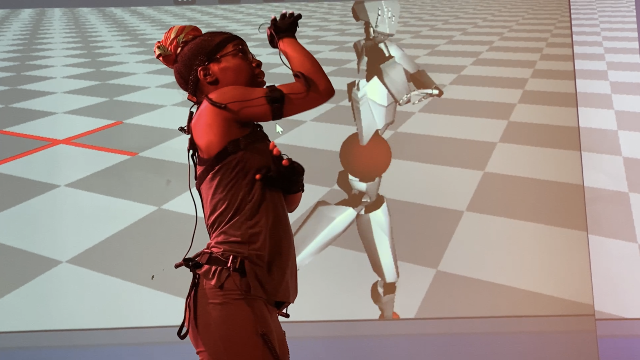 Dancer Roukijah Rooks wearing Perception Neuron motion capture suit and dancing in the Movement Lab in front of a projected image of her motion capture avatar. 