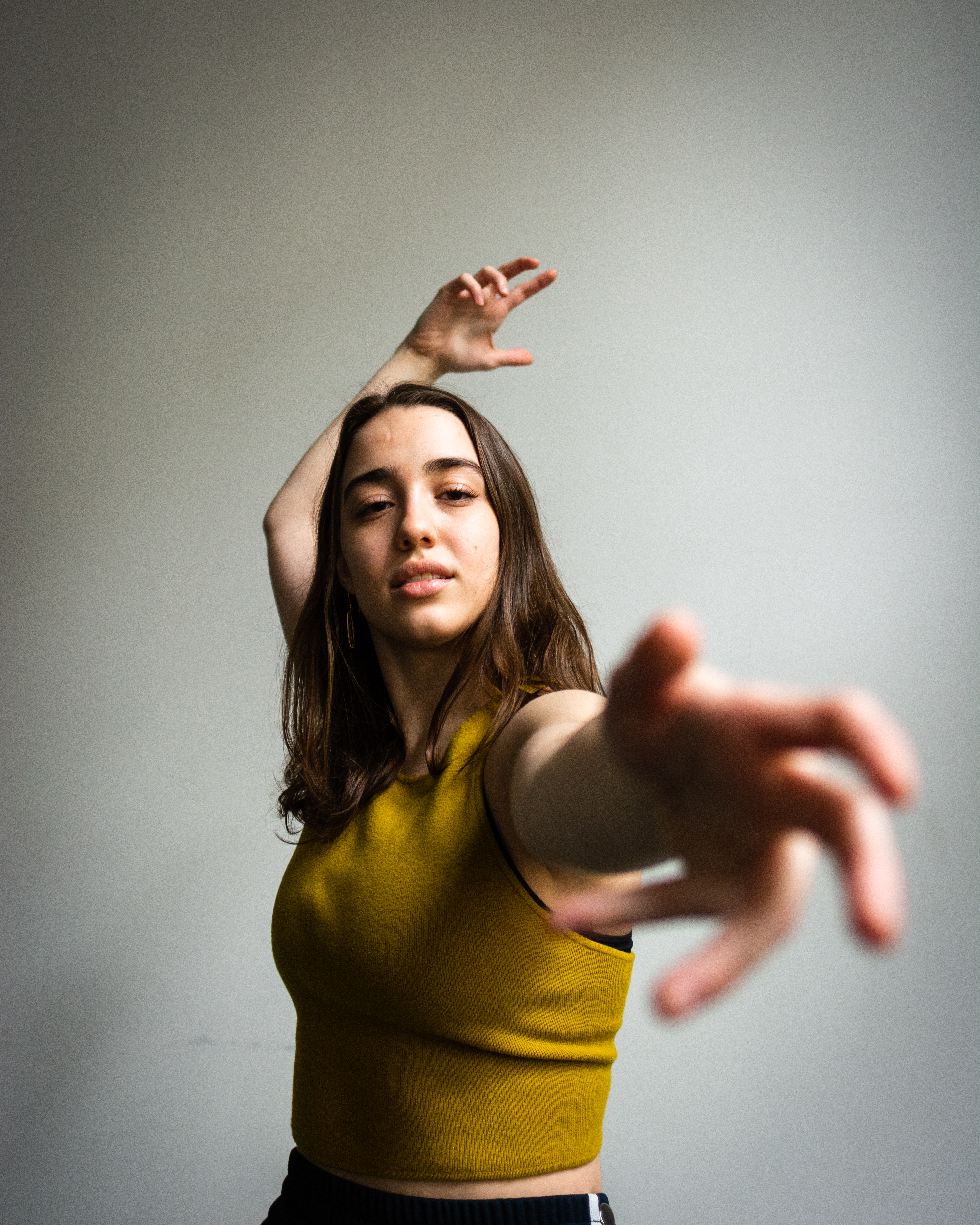 Allison Costa dancing, reaching towards the camera, wearing a yellow shirt 