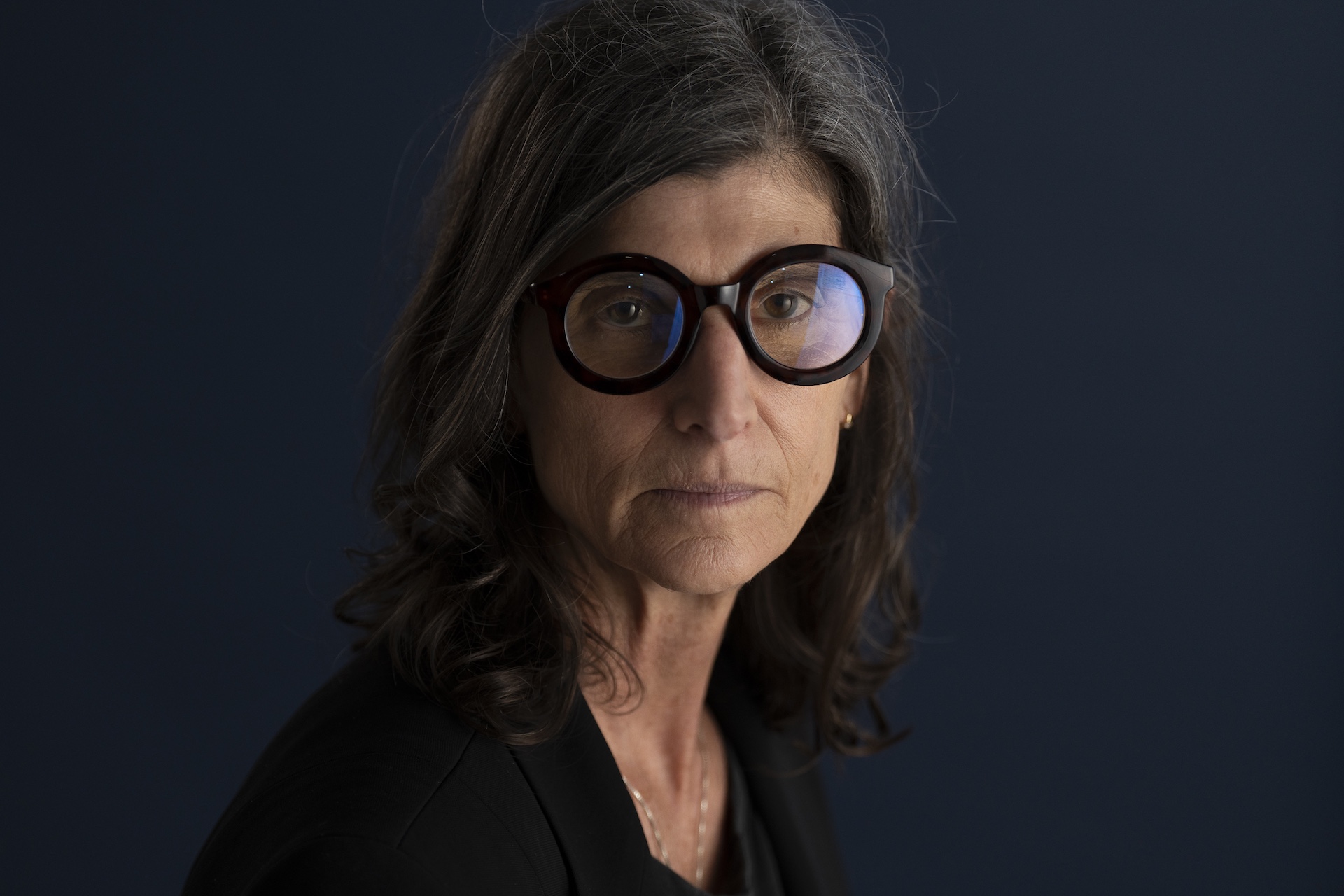 Close up photo of woman wearing black top and black framed glasses