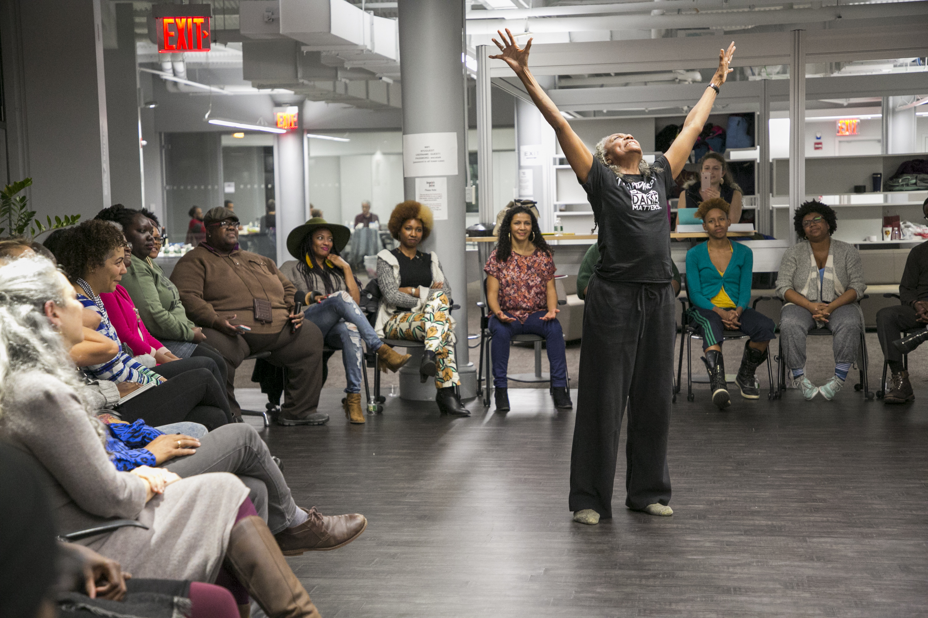 Dr. Brenda Dixon Gottschild raises her arms to the sky, surrounded by a circle of Dancing While Black community members at Dancing While Black: This Body Knows Freedom - Story Circles on Organizing toward Vision in an Age of Resistance at NYU's Hemispheric Institute in November 2017. Photo by Whitney Browne.