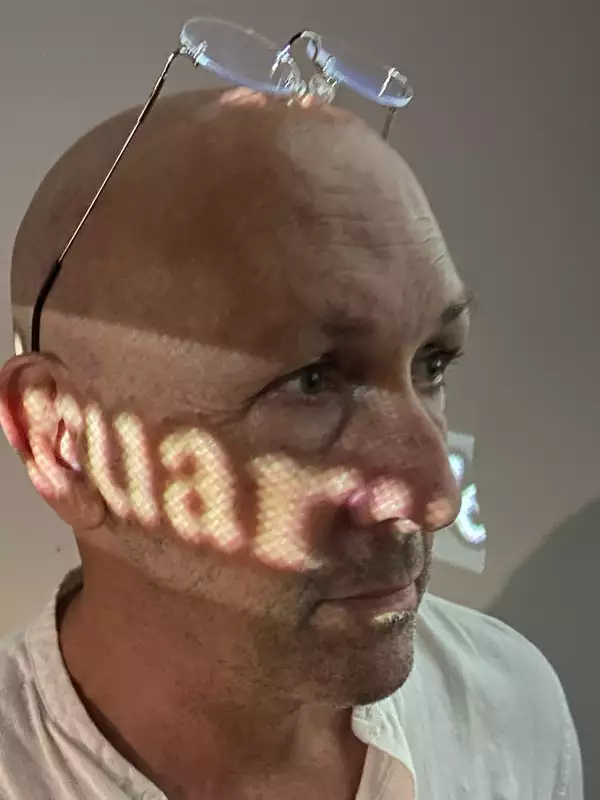 Guy de Lancey headshot with an incomplete projected word across his face